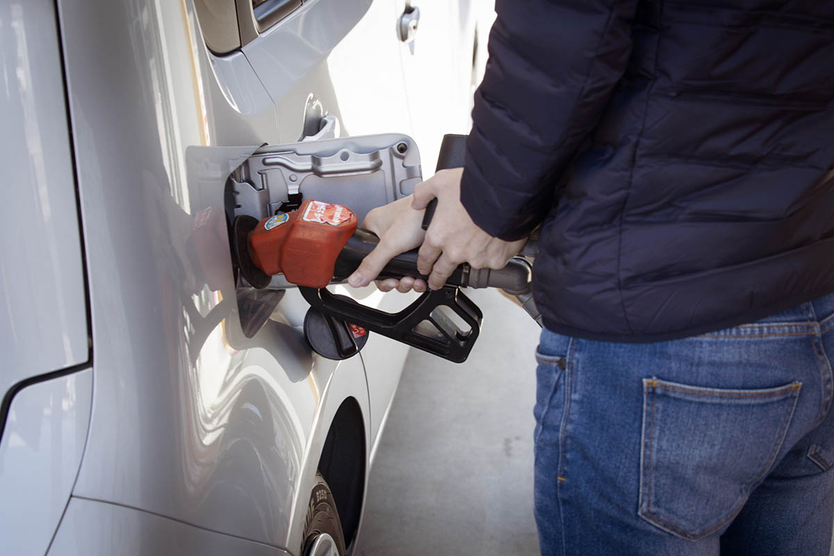 Person filling vehicle with gas at a gas station