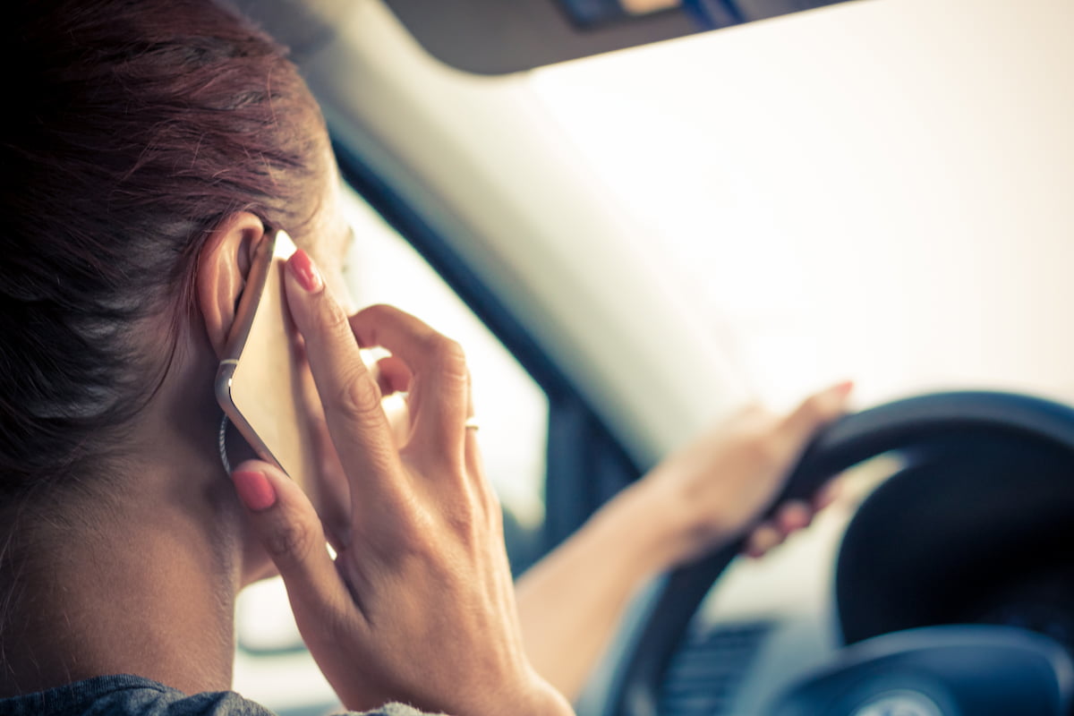 Person holding and looking at phone while driving