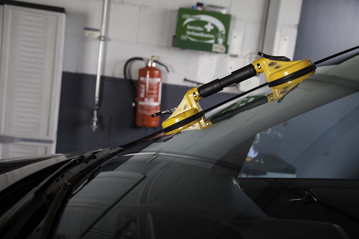 brand new windshield being installed on a car in garage