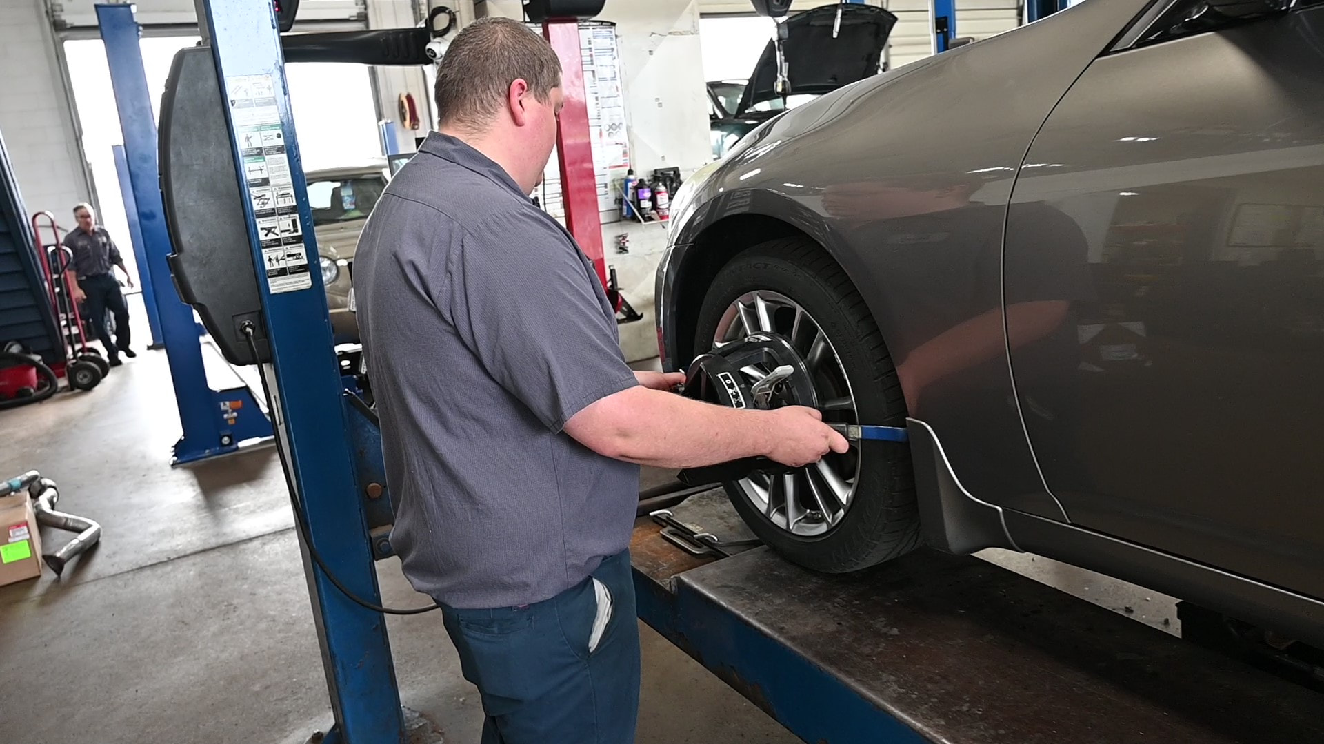 Mechanic performing computerized wheel alignment on a gray sedan at Matthews Tire in Appleton, WI.