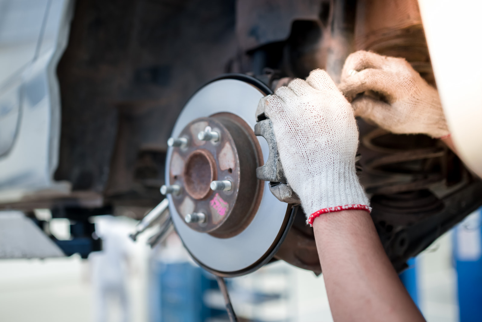 Auto technician tightening brake caliper over new rotor during brake service in Appleton, WI.