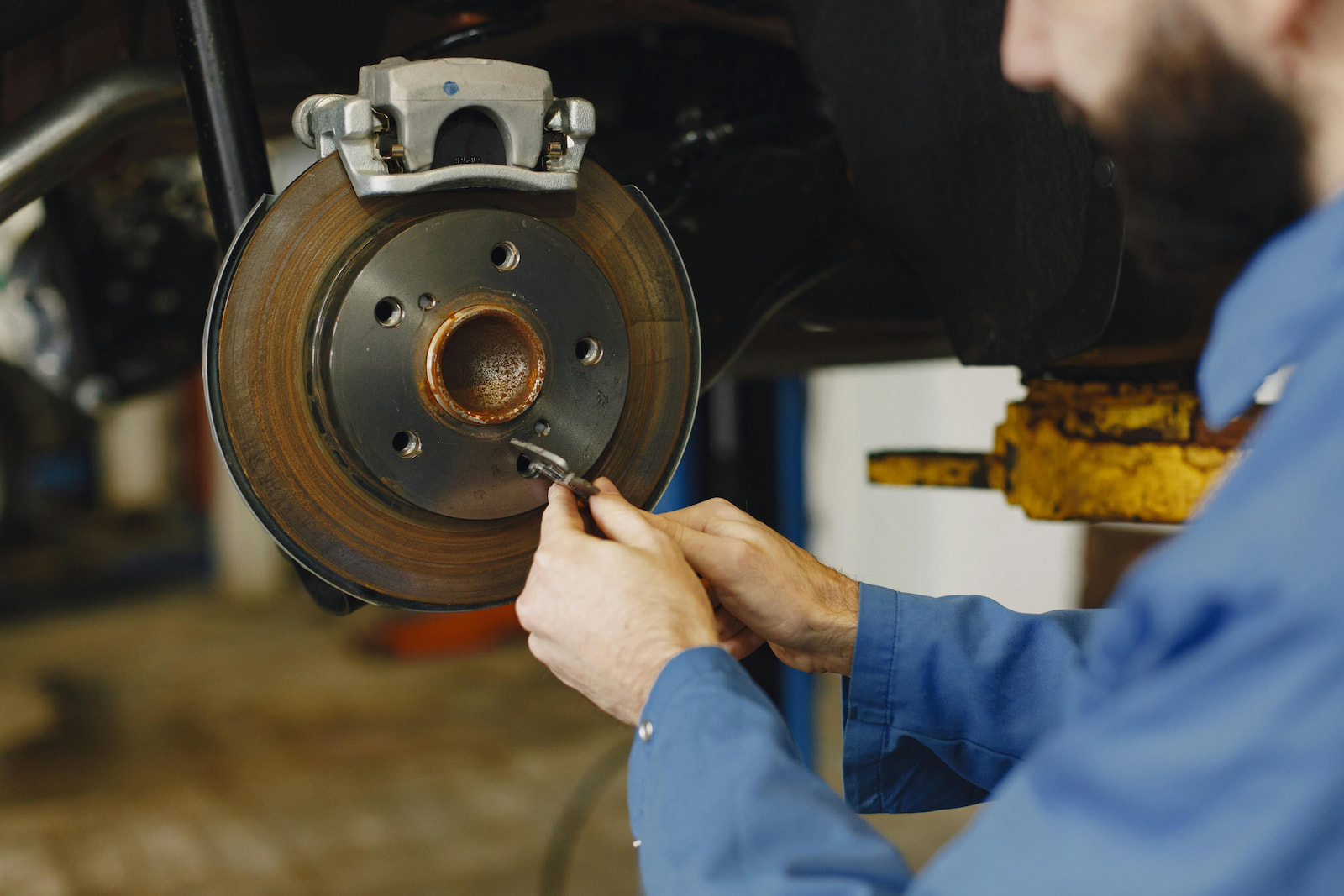 Mechanic working on front brake rotor and caliper assembly in Green Bay, WI auto repair shop.