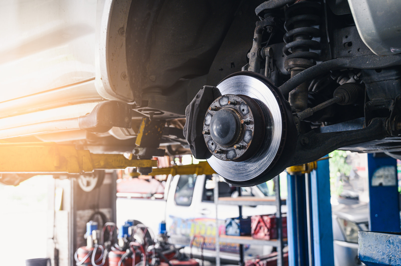 Vehicle on lift with exposed brake rotor and caliper inside Fond du Lac, WI auto repair shop.