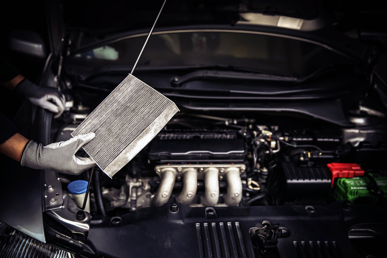 Technician removing a dirty cabin air filter during car AC service in Appleton, WI.