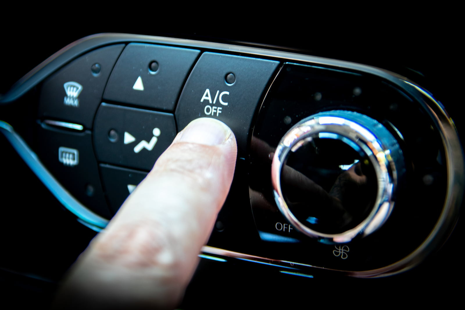 Finger pressing AC off button on car dashboard during AC service in Fond du Lac, WI.