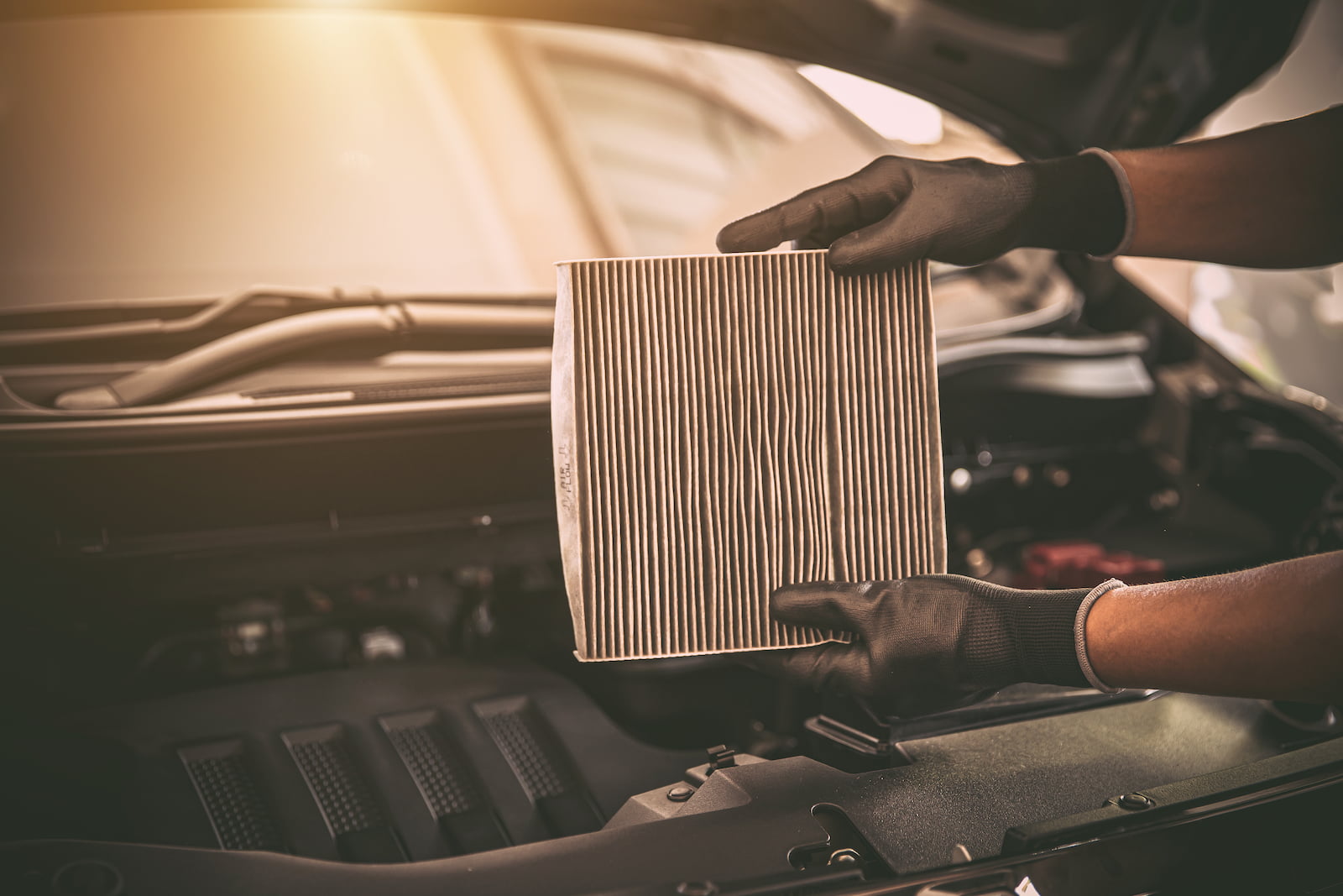Technician holding a dirty cabin air filter during car AC service in Green Bay, WI.