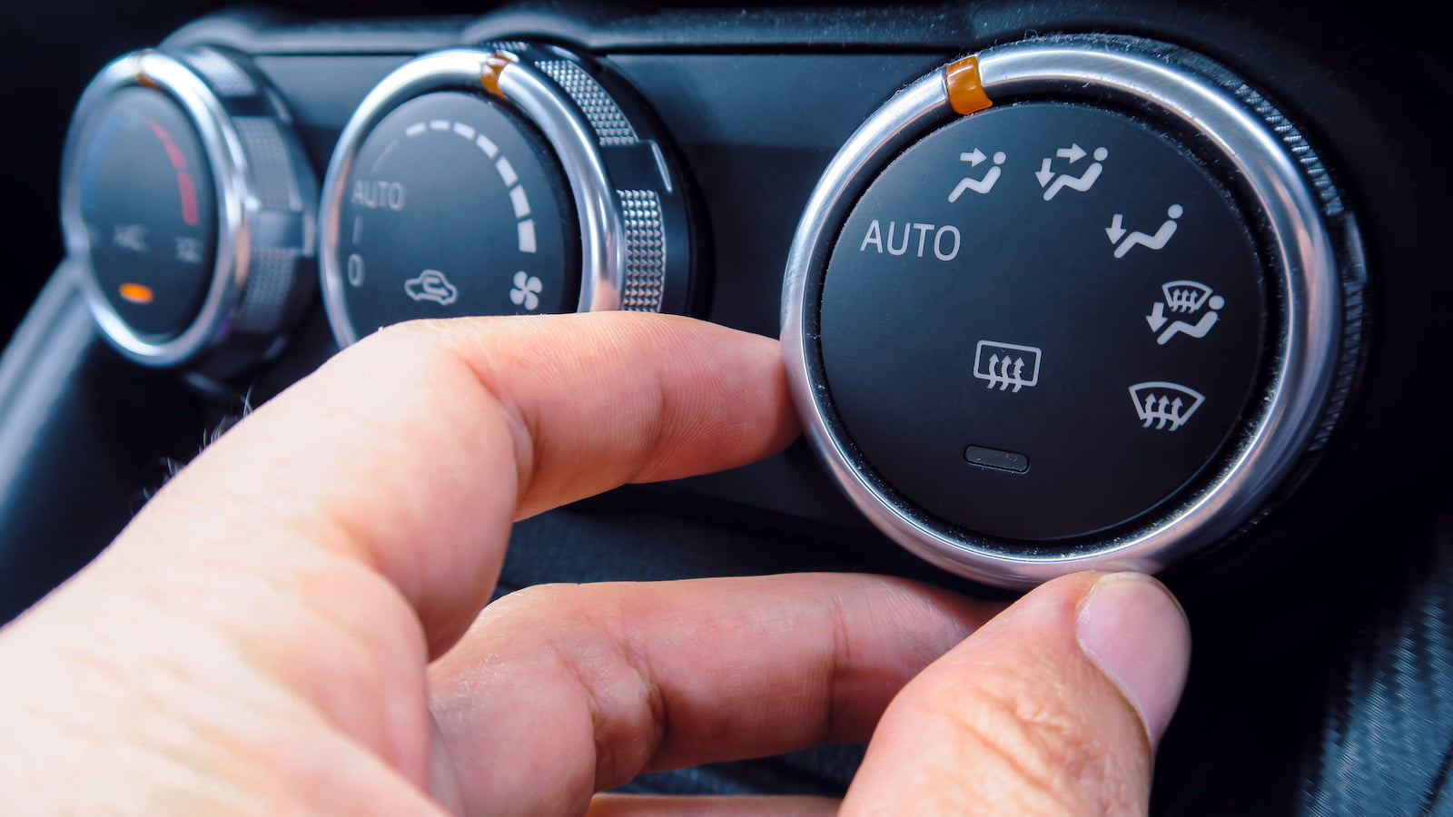 Close-up of driver adjusting car dashboard climate control settings in Menasha, WI.