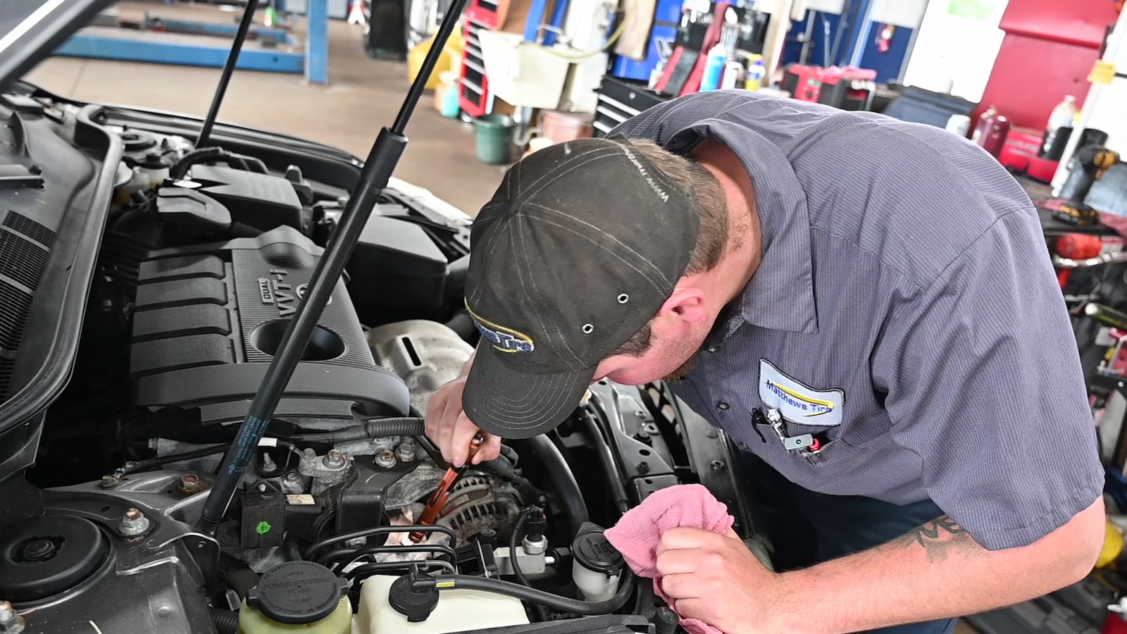 Matthews Tire technician checking engine during car AC inspection in Menasha, WI.