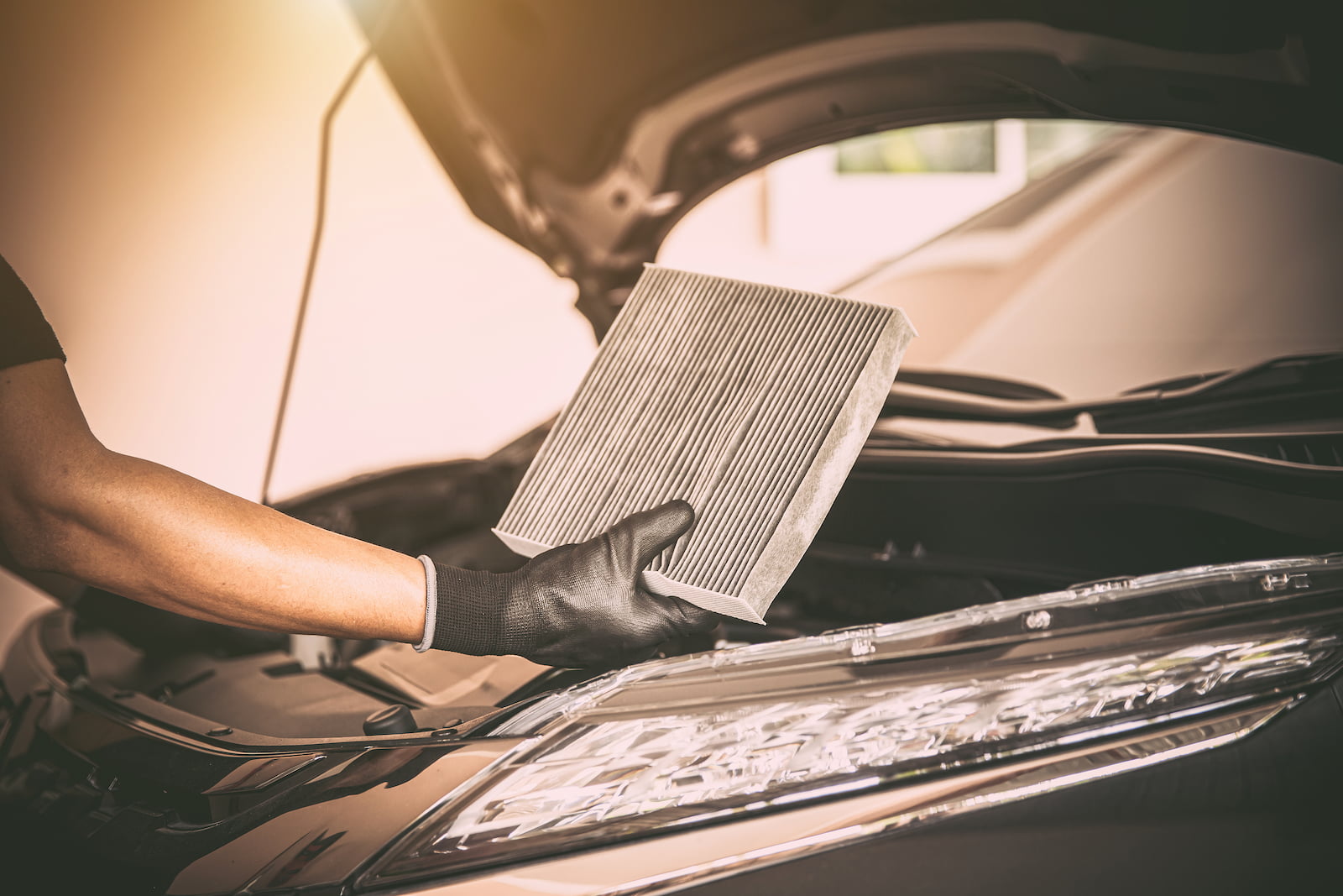 Technician holding a dirty cabin air filter during car AC repair in Waupaca, WI.