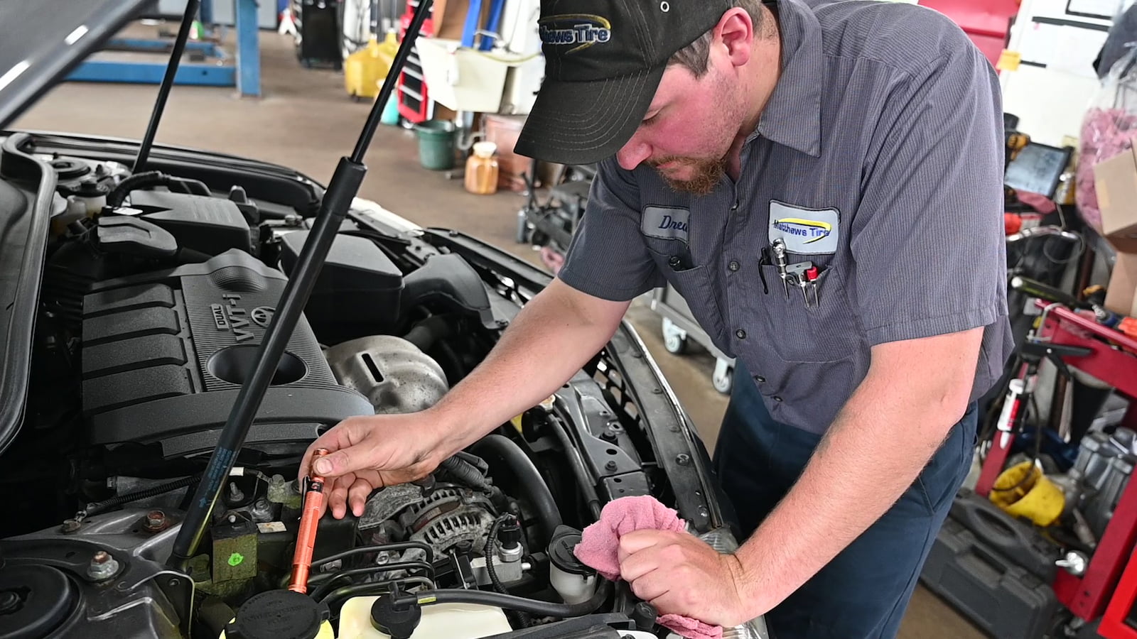 Matthews Tire technician checking engine components during AC service in Waupaca, WI.