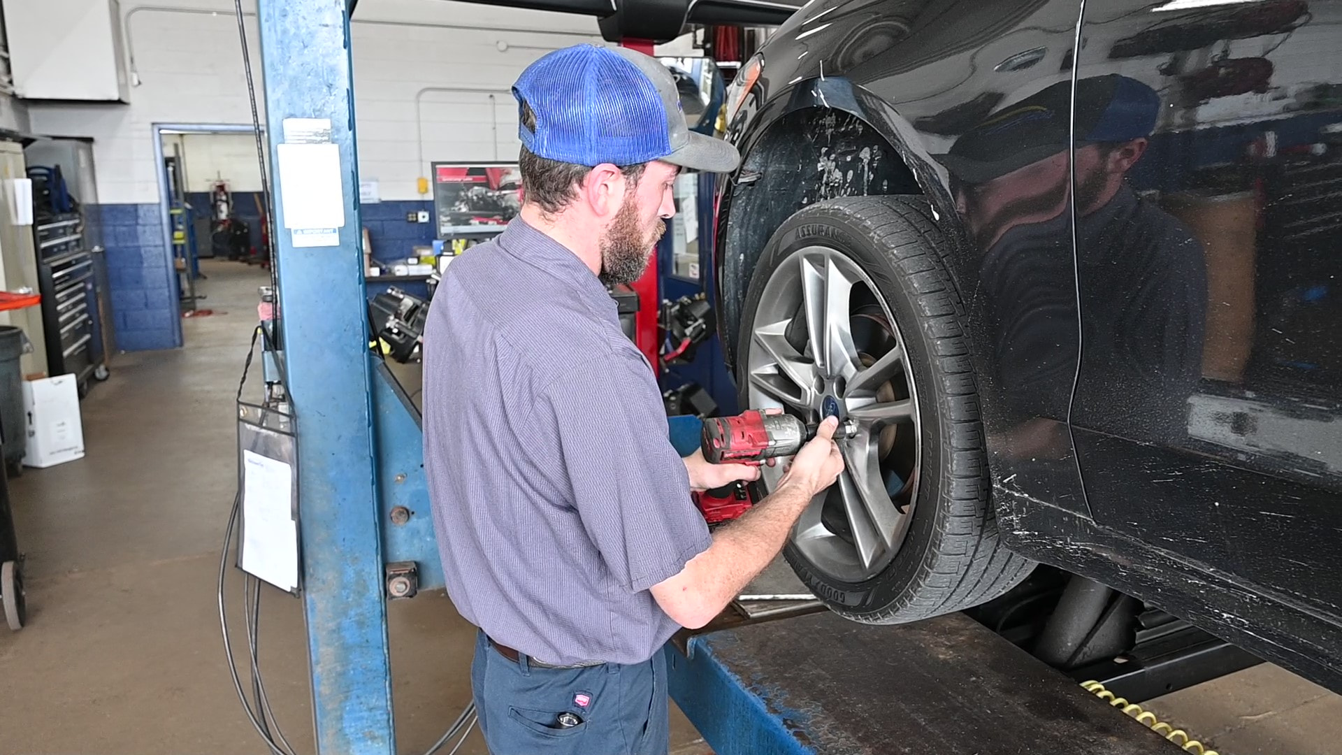 Technician using power tool to rotate car tires in professional shop in Fond du Lac, WI.