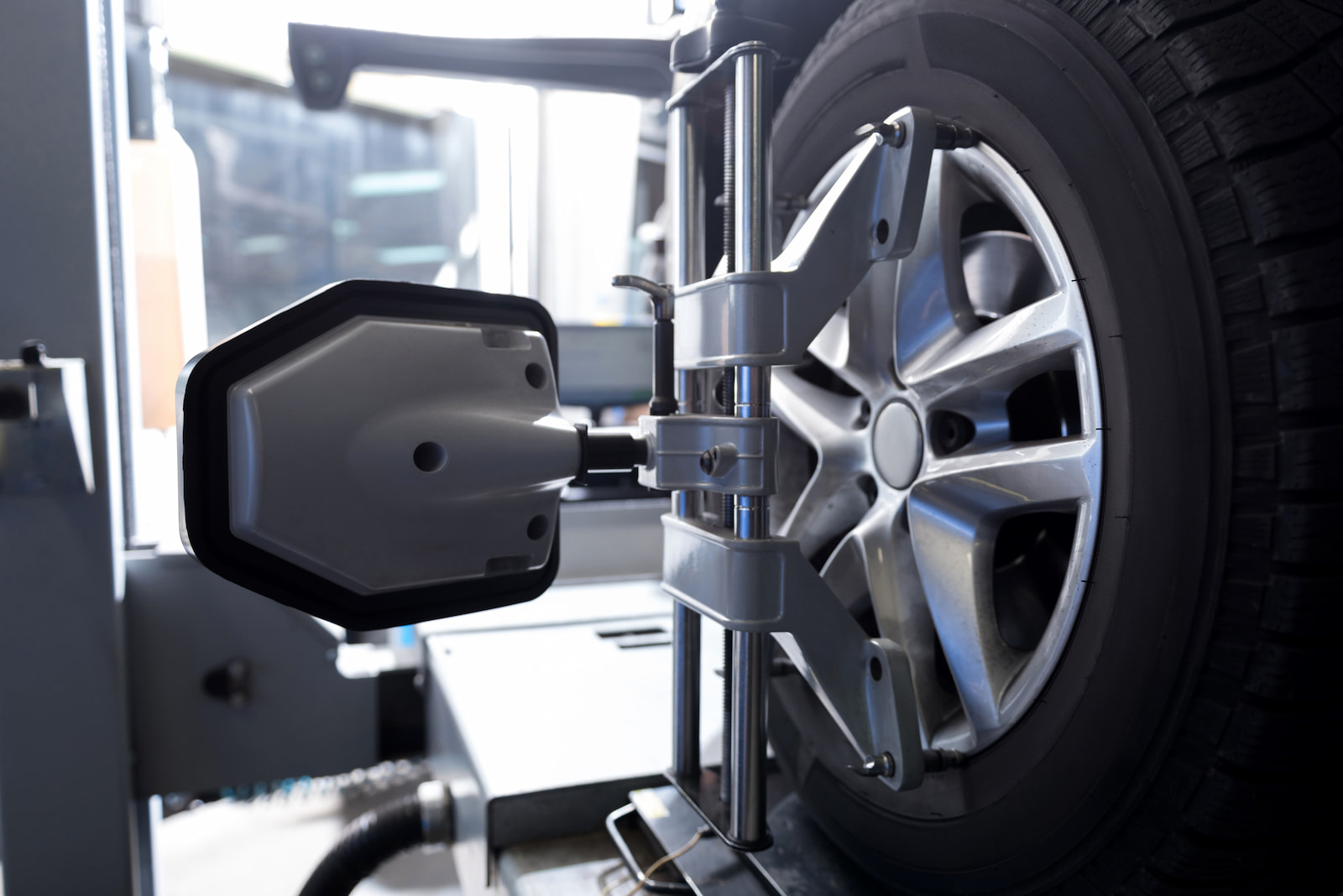Digital alignment sensor mounted on alloy wheel during vehicle suspension check.