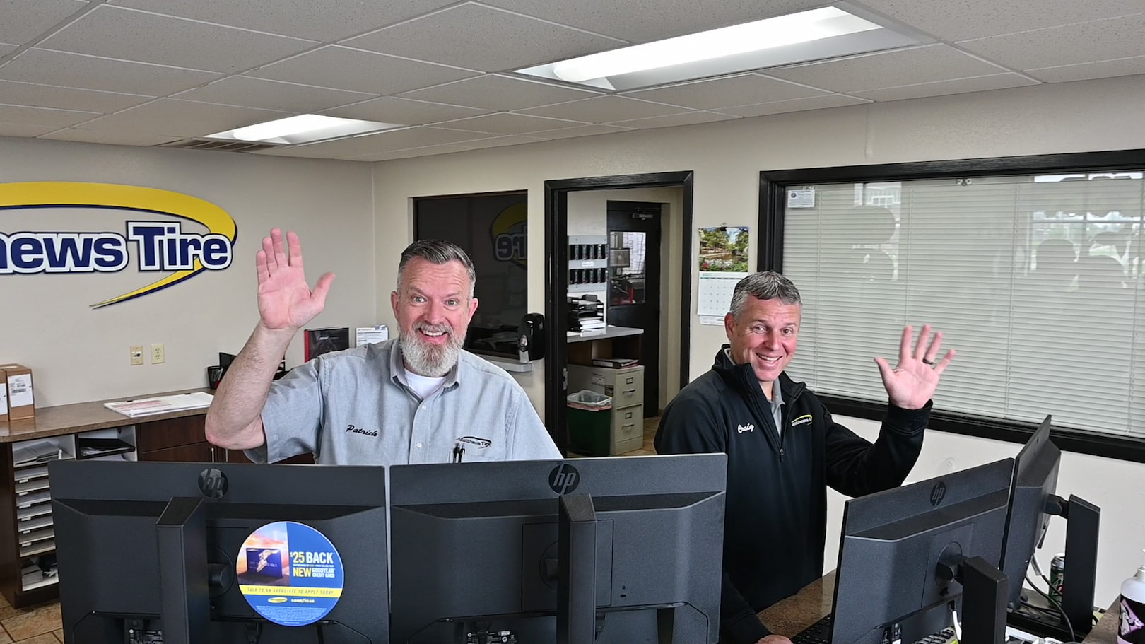 Two friendly staff members greet customers at front counter of Waupaca tire shop.