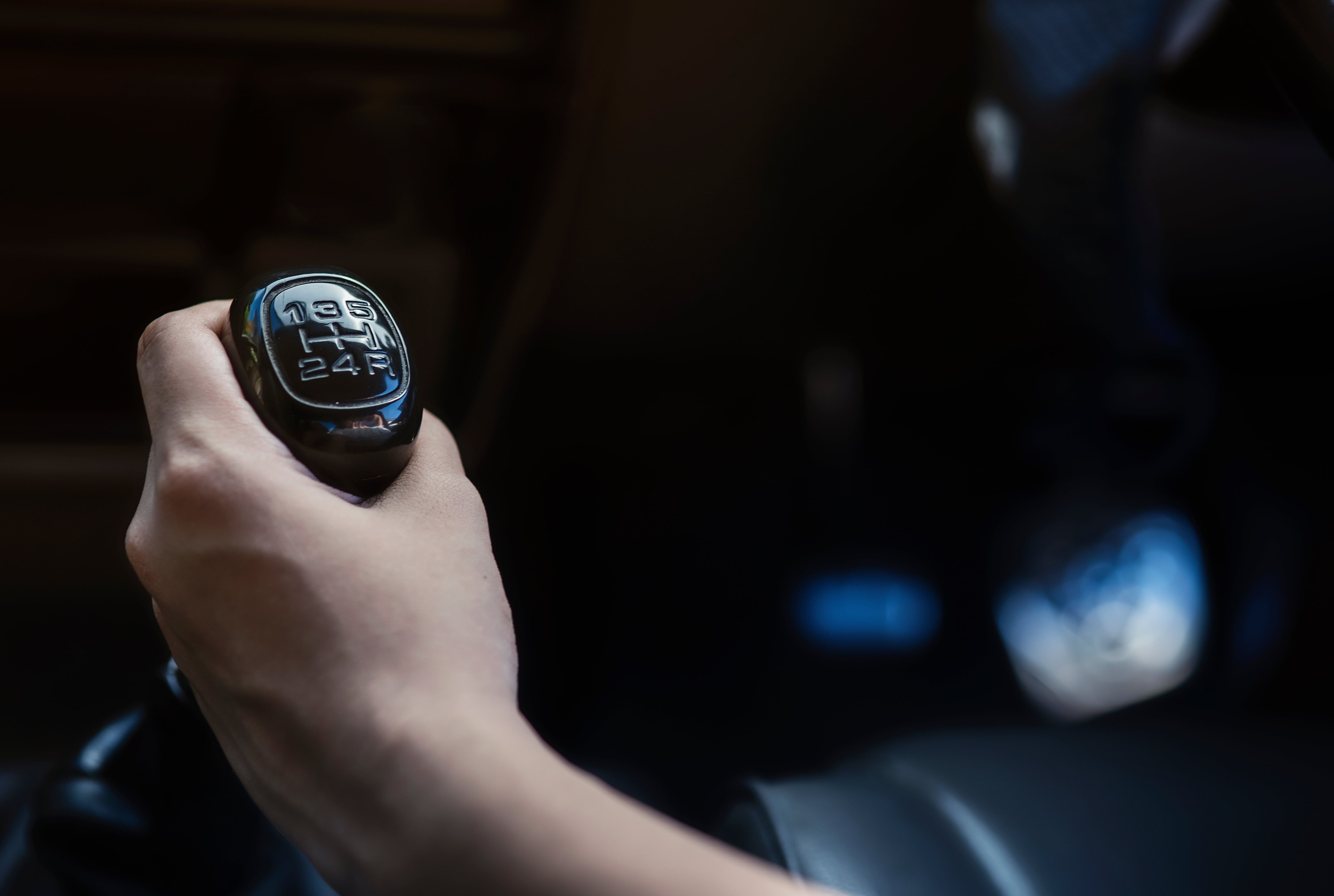 Hand on manual gearshift during vehicle transmission service in Menasha, WI.