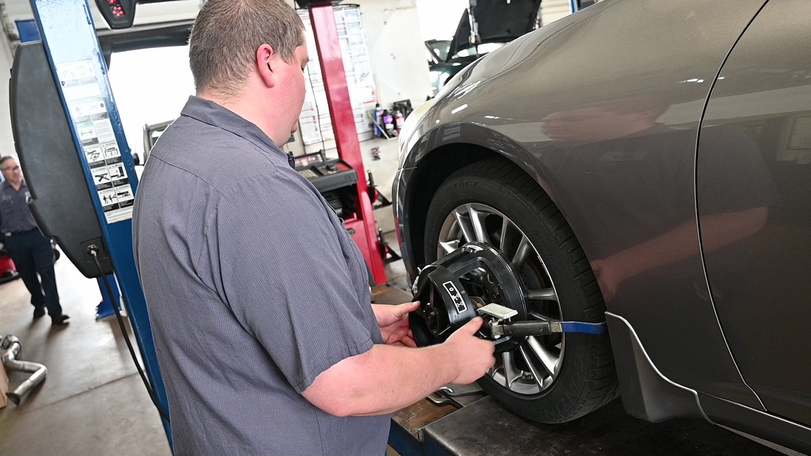 Auto technician fine-tuning alignment sensor on car wheel in Green Bay, WI.