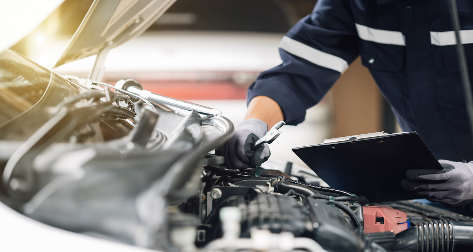 Auto technician inspecting engine components with a checklist during an oil change in Green Bay, WI.