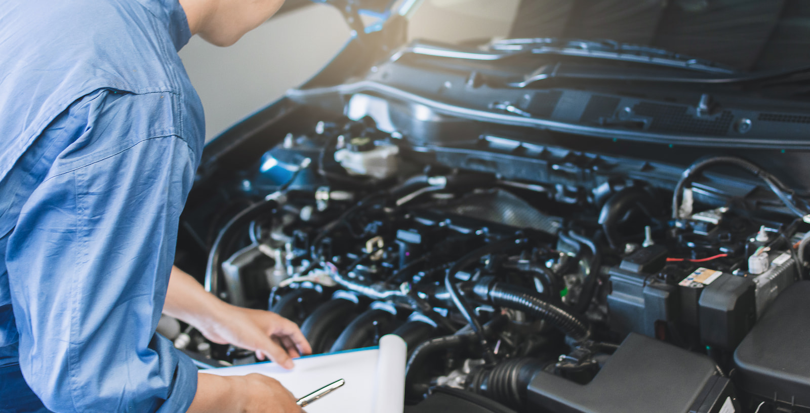 Auto technician inspecting engine components during an oil change service in Appleton, WI.