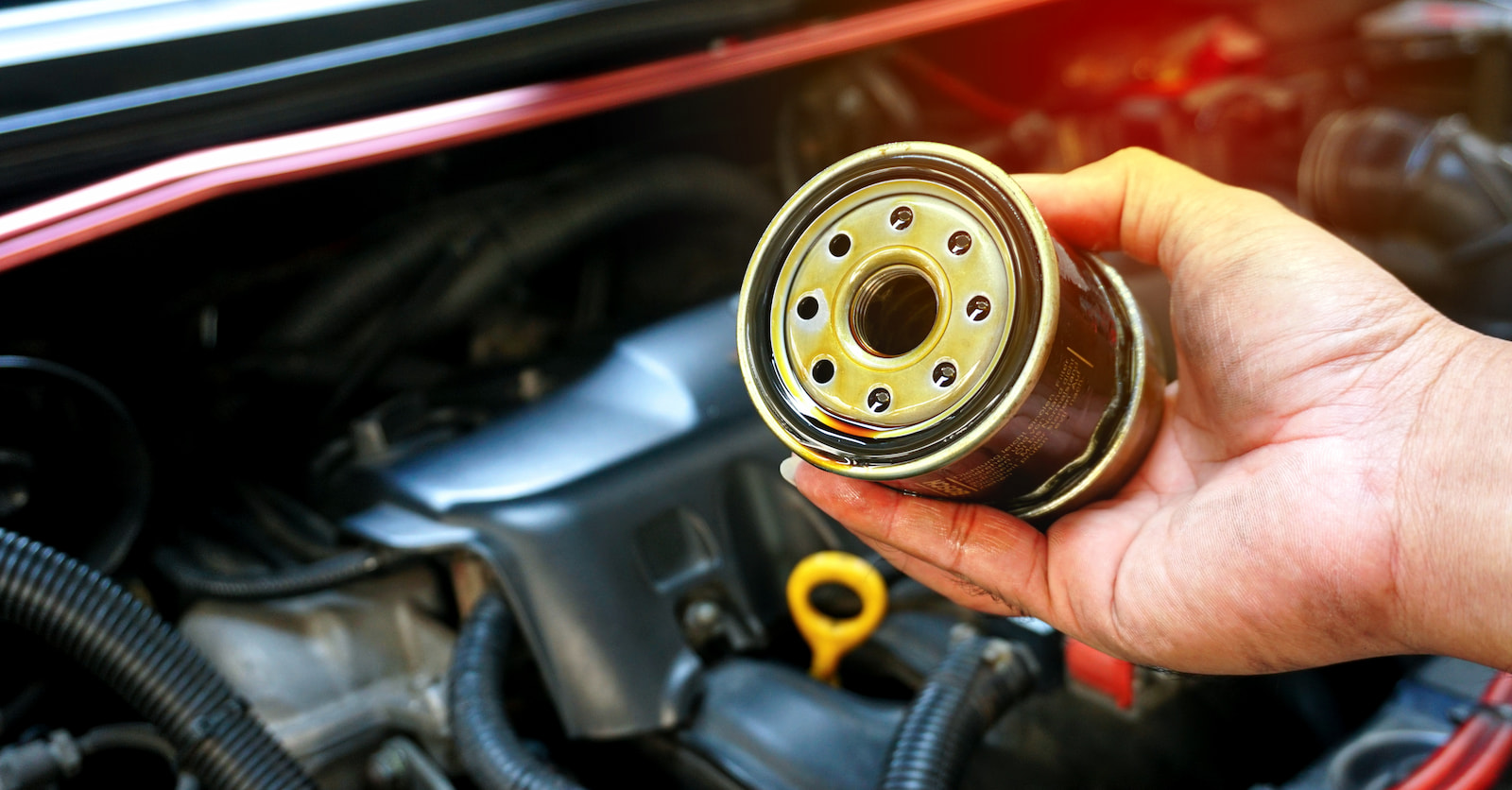 Mechanic holding a used oil filter during an oil change service in Green Bay, WI.