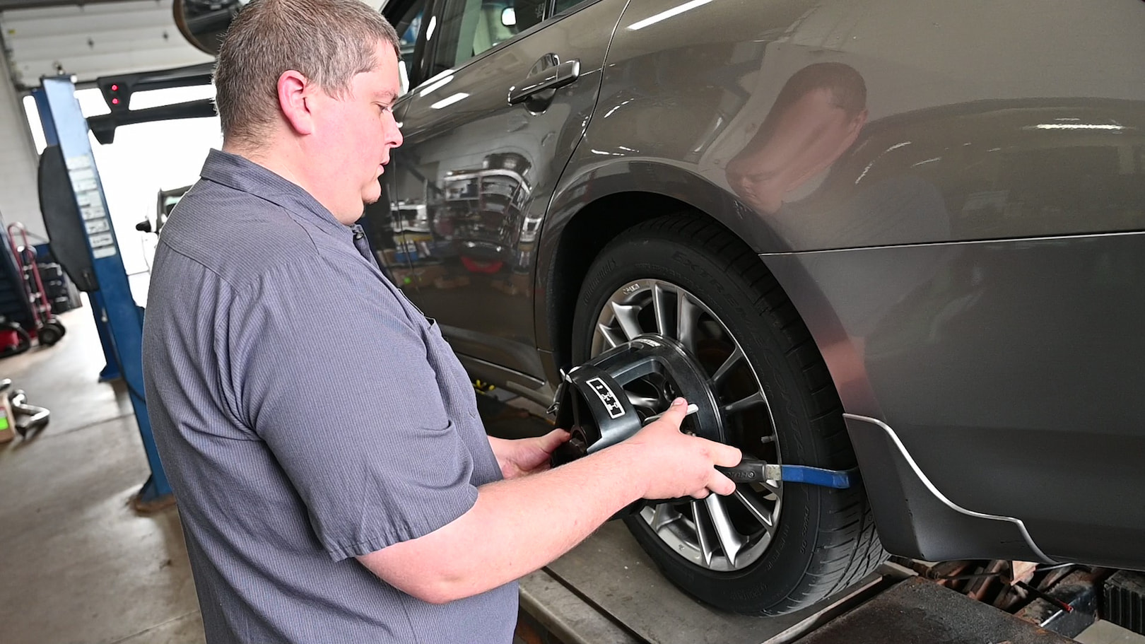 Technician installing alignment sensor on car tire for wheel alignment in Fond du Lac, WI.