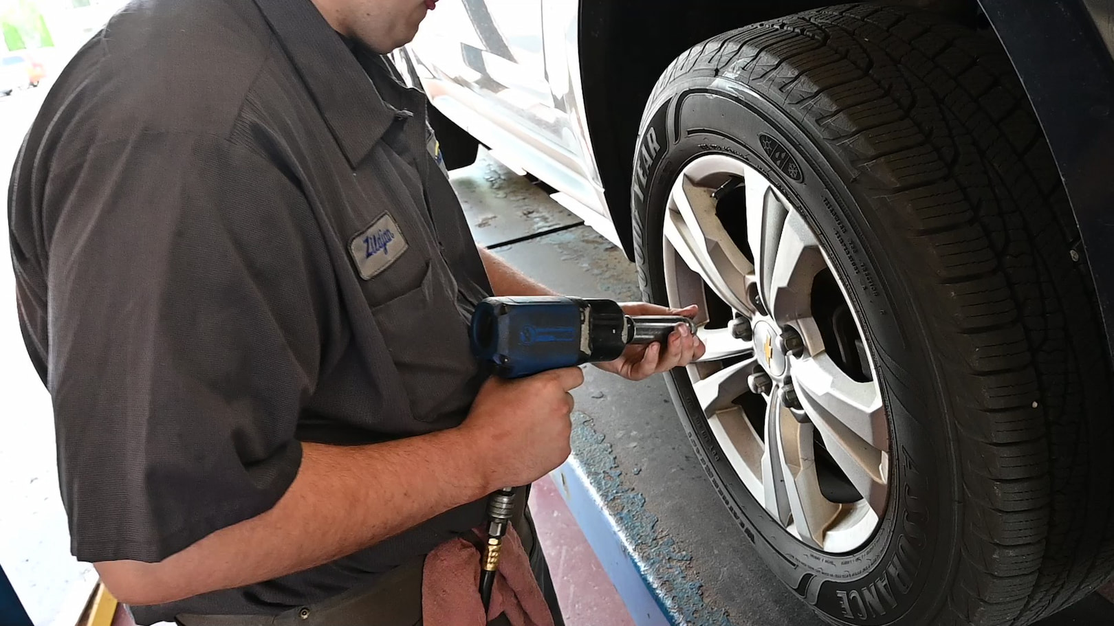 Mechanic loosening lug nuts on raised vehicle during tire rotation in Waupaca, WI.