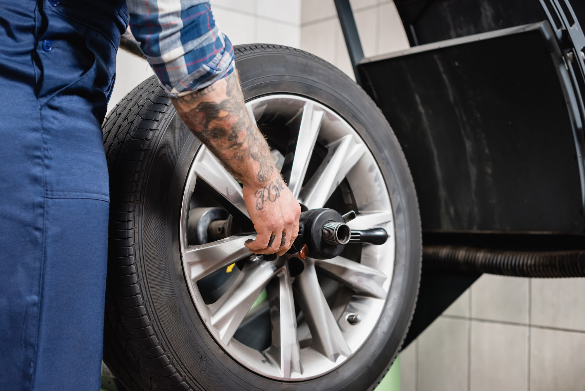 Auto technician performing tire balancing on alloy wheel at repair shop in Appleton, WI.