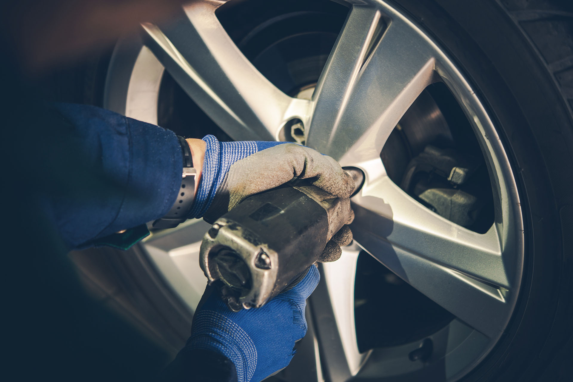 Person torquing down lug nuts while performing a tire rotation service