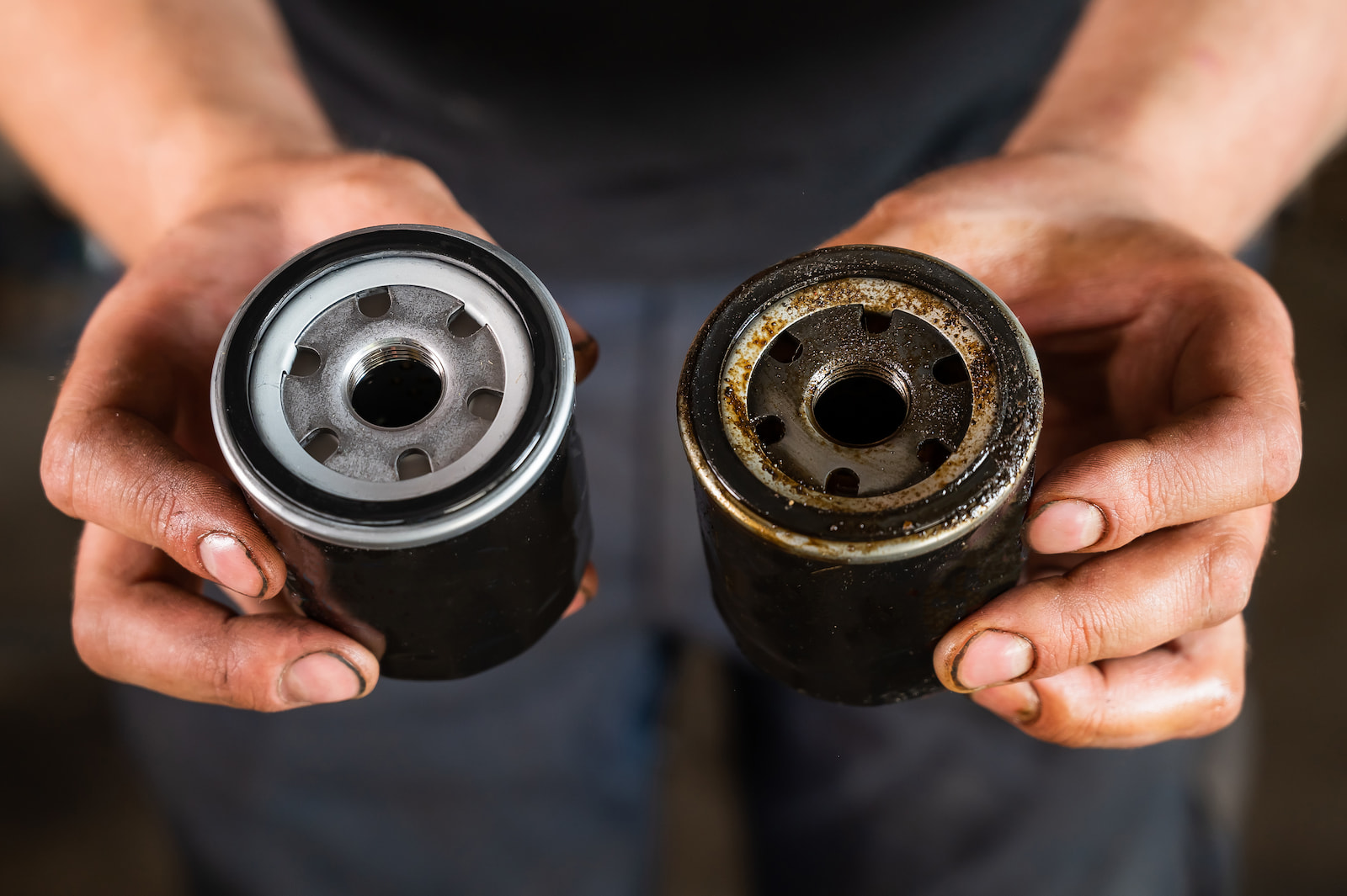 Mechanic holding a used and new oil filter during an oil change service in Fond du Lac, WI.