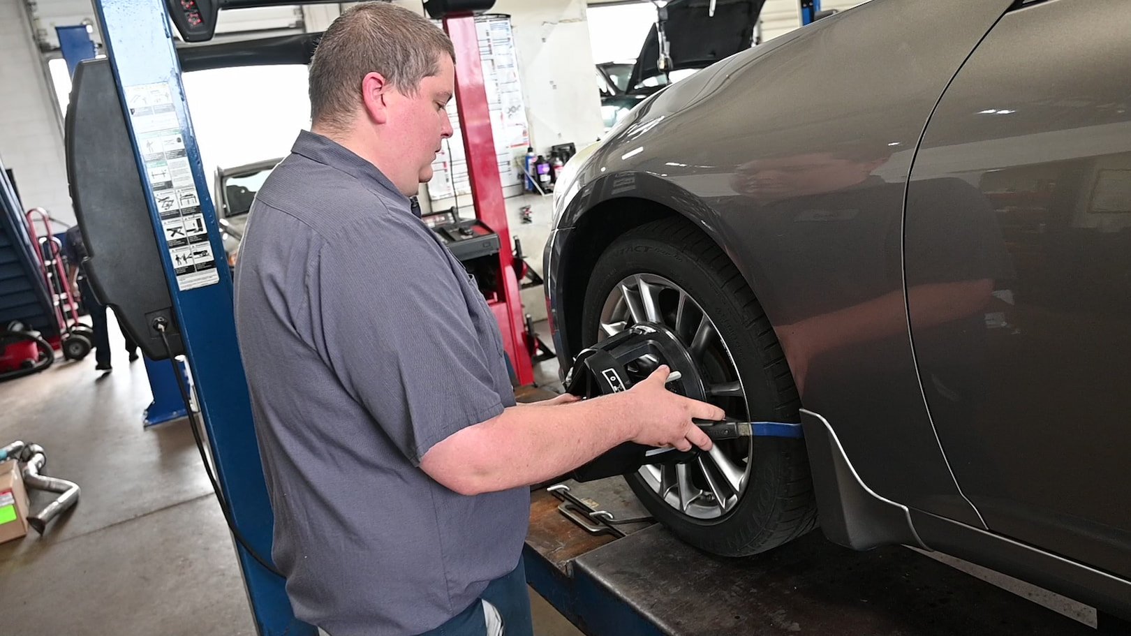 Matthews Tire technician adjusting alignment sensor for precision wheel alignment in Menasha, WI.