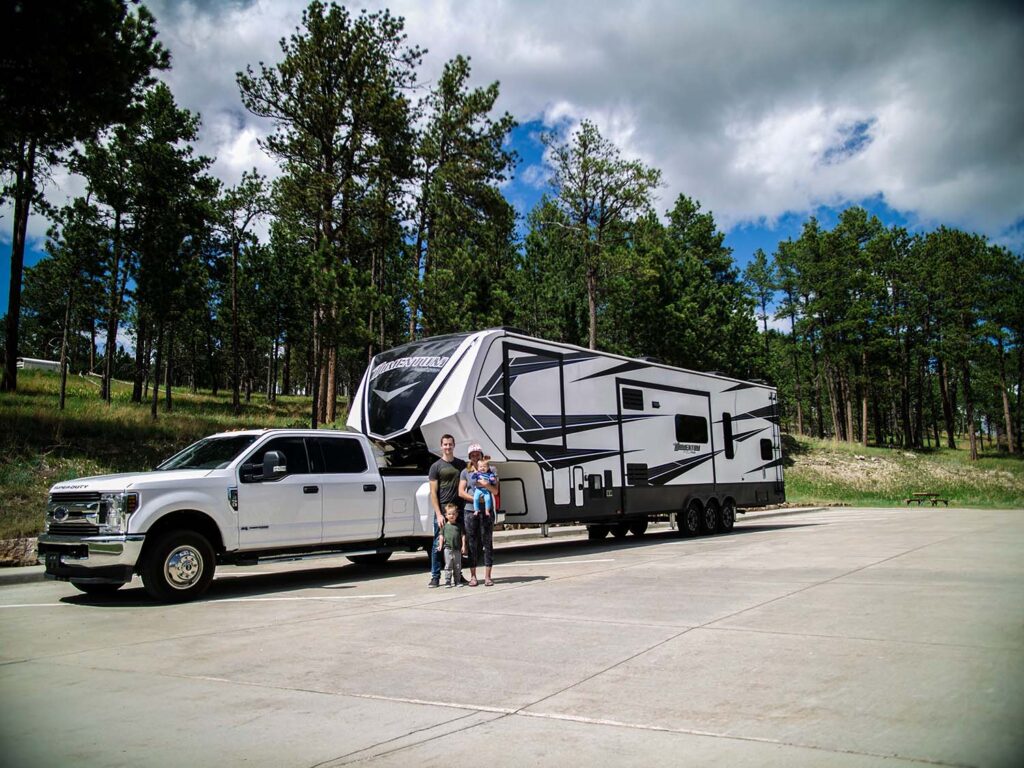 family-standing-in-front-of-truck-and-camper