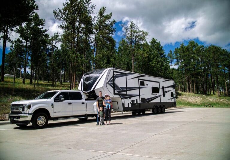 family-standing-in-front-of-truck-and-camper