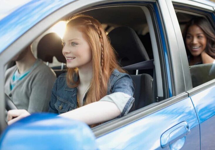 young-woman-driving-car-with-friends